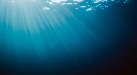 Serene underwater scene with sunlight streaming through the deep blue ocean, creating luminous rays and a natural light bokeh effect