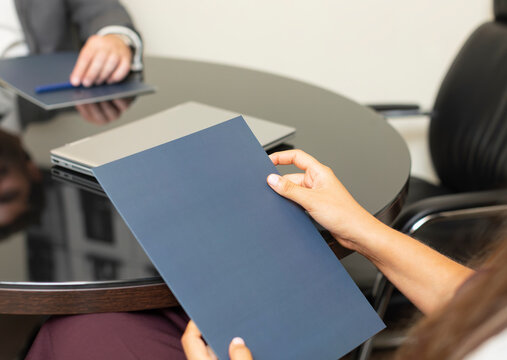 Meeting in an office with two people discussing important documents and using a laptop over a round table