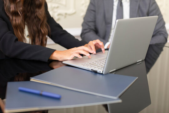 Business meeting takes place with two people working on a laptop in a modern office setting during afternoon hours