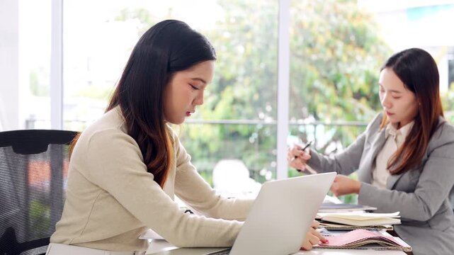 Young asian female interior designer or architect working on creative project with drawing, material sample , laptop computer in office. Business of Real estate, home decoration , renovation concept.