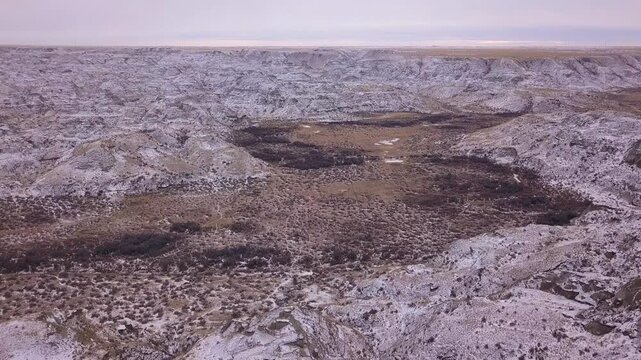Flyover badlands valley bottom criss crossed with game trails in snow