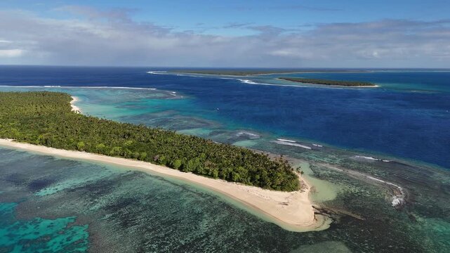 Aerial drone view above the turquoise shoreline of Eua, Kingdom of Tonga, where crystal-clear water reveals coral formations beneath the surface near the untouched tropical coast.