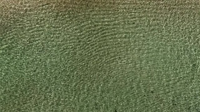 Top-down drone view of pure turquoise water near Eua Island, Kingdom of Tonga, capturing crystal-clear tropical sea surface with minimalistic composition and serene Pacific atmosphere.