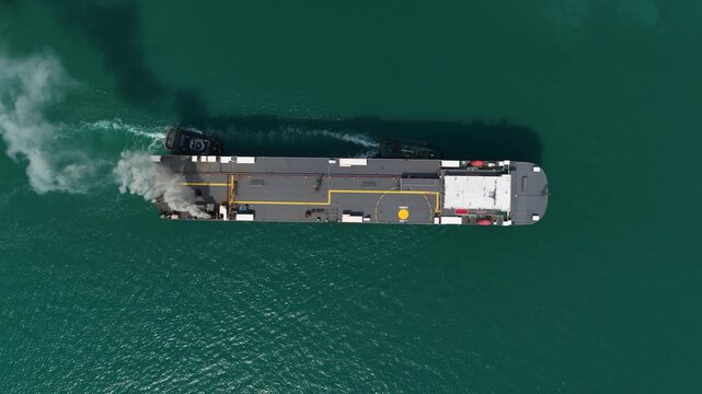 Cargo ship sailing on green water aerial view