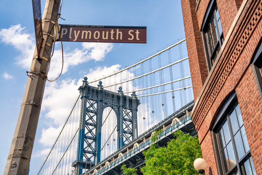 Manhattan Bridge between Manhattan and Brooklyn over East River seen from a narrow alley enclosed by two brick buildings on a sunny day at Washington Street and Plymouth Street in DUMBO, Brooklyn, NYC