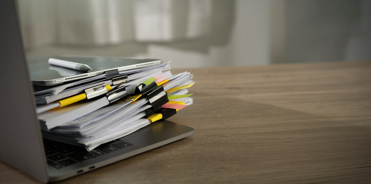 stacked documents compliance with stack of files and tabs on laptop , representing due diligence review, records management, business workflow overload