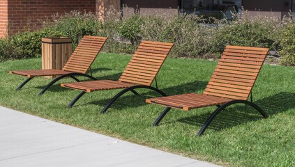 Wooden lounge chairs sit on a green lawn near a walkway