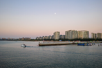 Fototapeta premium Boats at sunset in Qingshuiwan Bay with Lingshui cityscape, Hainan Island, China