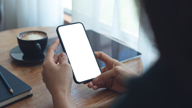 Mockup, Woman using mobile phone with blank white screen while online working on digital tablet at coffee shop. Business woman using smartphone, mockup for mobile app marketing, closeup