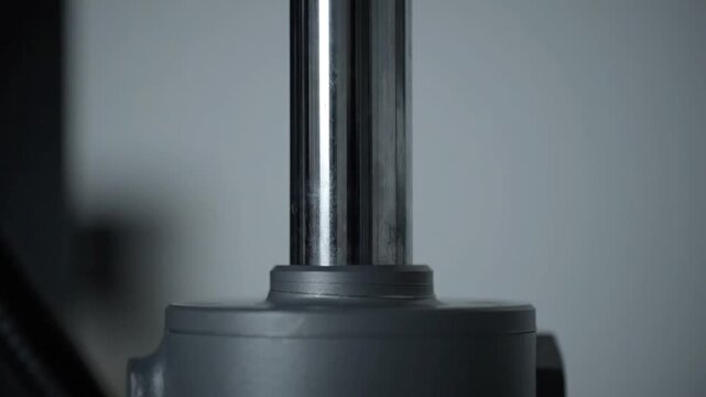 Close-up of hydraulic cylinder extending and retracting, industrial machinery detail
