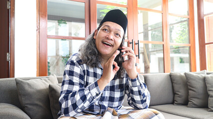 Obraz premium Asian moslem man making a phone call to family and friends to say grace during Idul Fitri celebration