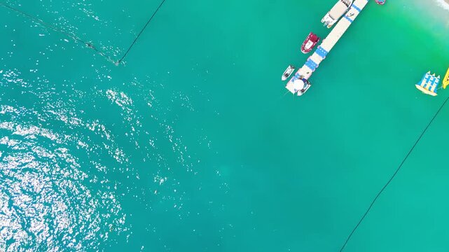 Oludeniz, Turkey. Aerial top down view of vibrant Oludeniz Beach with rows of blue umbrellas, crowded pebble shore, people swimming and sunbathing, beach bar and turquoise sea waves, summer.. Aerial 