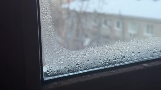 Fogged up plastic windows with condensation. Frost outside, warm inside. Moisture droplets on double-glazed windows in winter.
