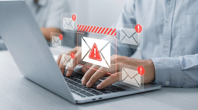 Person typing on laptop with spam email warning icons