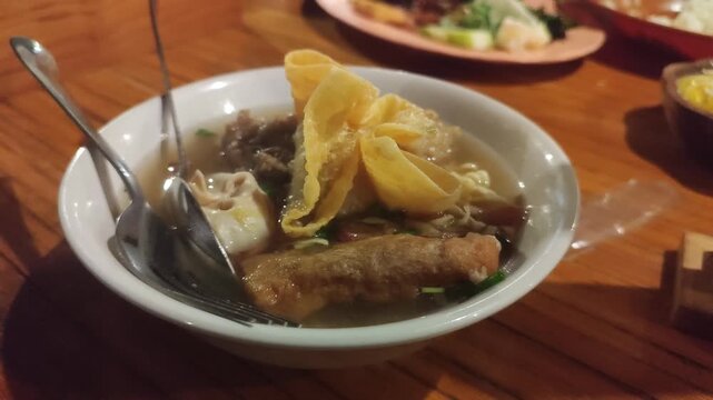 Hot Indonesian meatball soup served during cold weather, creating warm comfort food atmosphere and delicious culinary experience.