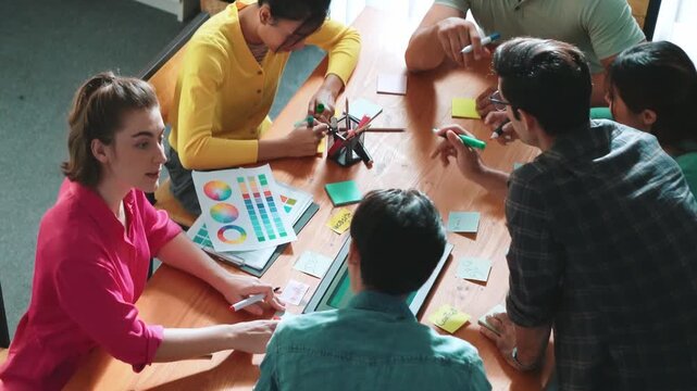 Top view of manager writing idea on sticky notes and explain idea about web design. Professional marketing team or programmer brainstorming idea while looking at tablet with color palette. Symposium.