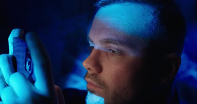 Cinematic close-up of a man watching a TV series on his smartphone at night, illuminated by blue screen light, representing late-night streaming and digital lifestyle.