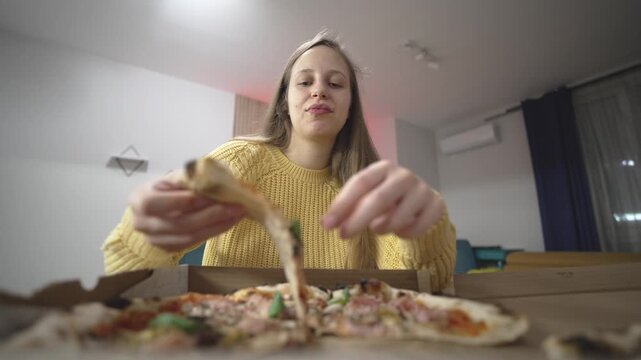 Woman reaches for a slice of pizza from a fast food order, holding it ready to eat, capturing casual meal, fast food enjoyment, and quick snack lifestyle.