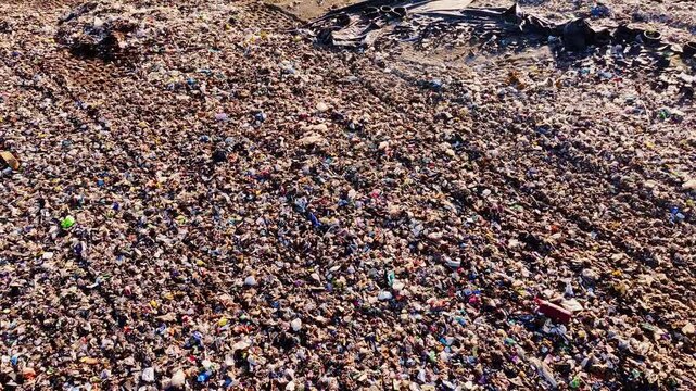 Cinematic drone tilt up over landfill at sunrise exposing environmental damage