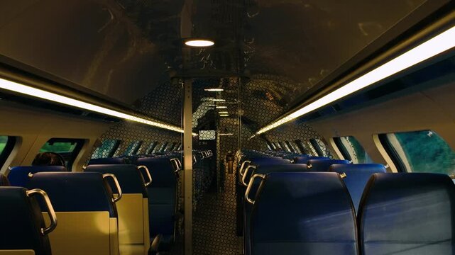 Passenger cabin of modern train with blue upholstery and decorative glass dividers. Symmetric view of seating arrangement in Dutch railway carriage. High quality public transportation interior.