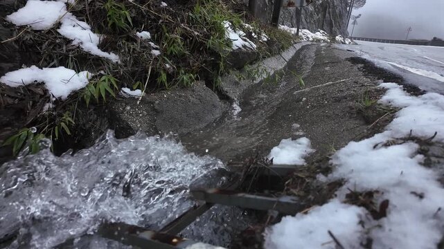 Melted ice water flowing into gutter in slow motion