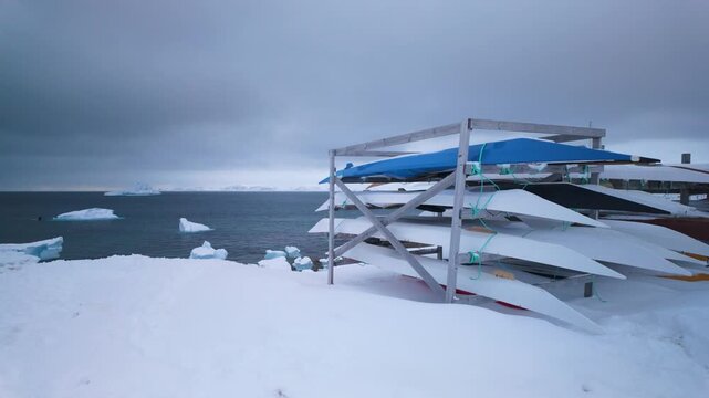 Kayaks by peaceful snowy shore and icy ocean in Nuuk, Greenland