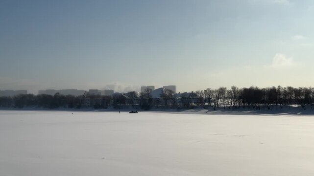 Panorama of a frozen river with a fisherman and a hovercraft