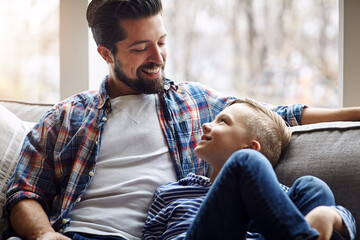 Obraz premium Father, boy and smile on sofa with home, happiness and bonding with parent on weekend break. Dad, son and child development with love, living room and family together for trust with care in lounge