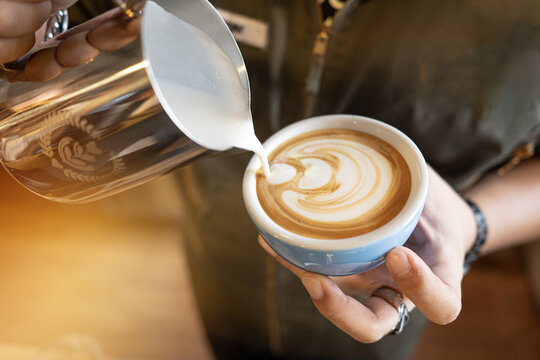 Latte coffee barista milk pour latte art espresso foam in blue cup, creamy heart pattern as steady hand guides steel pitcher, cozy cafe mood and inviting aroma create calm morning moment