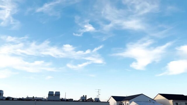 Serene blue sky with wispy clouds over suburban rooftops