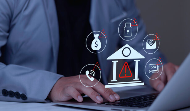 Businessman typing on laptop with bank fraud warning hologram displaying red alert icons on money, email, and phone. Concept of financial scam detection, cyber security, and phishing risk.