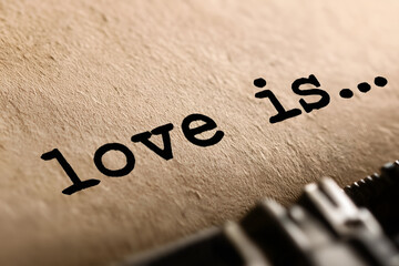 This image features a close-up of the phrase 'love is...' typed on paper, evoking deep emotions and thoughts about love.