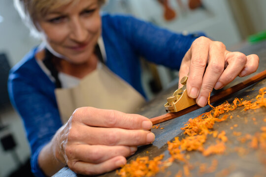 artisan woman shaving wooden baton with hand jack plane