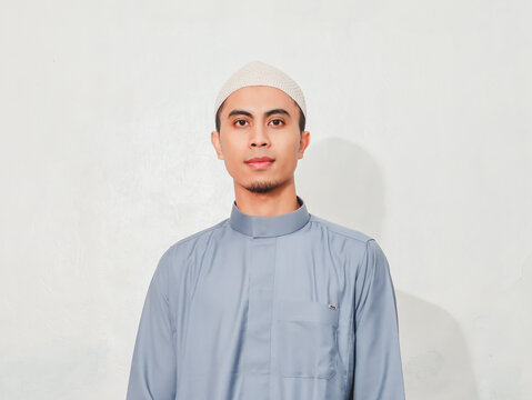 Muslim man standing and looking at camera in studio on white background for portrait, identity, culture, and advertising use.