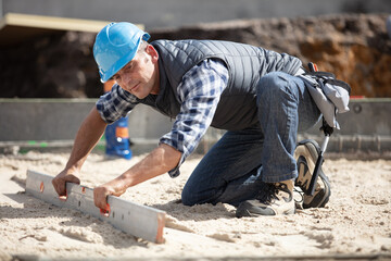 mason building using a wooden trowel and leveling