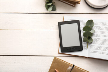 Modern e-reader with books and eucalyptus branches on white wooden background © Pixel-Shot