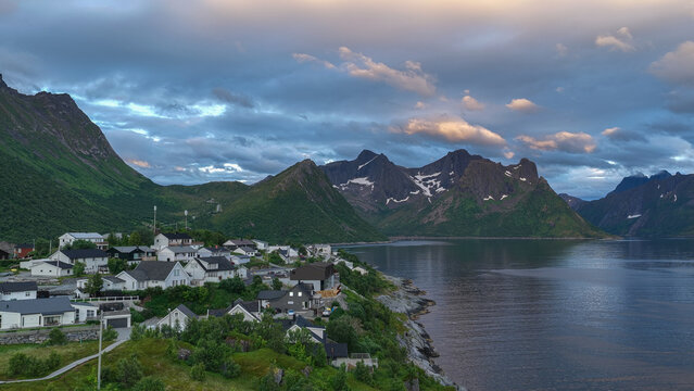 12 july 2025, Hus&oslash;y, Norway. Aerial, drone view of little village Husoy and island in &Oslash;yfjorden fjord during sunset. Beautiful nature, mountains surrounding fjord, wonderful golden reflection in the w