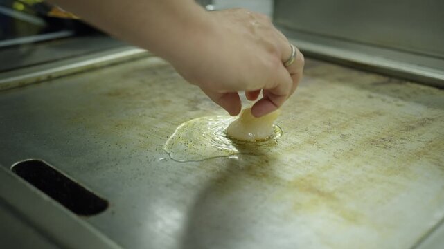 Slow motion shot of scallops that are placed on a griddle in a fine dining kitchen