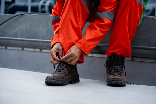 A man in an orange jumpsuit is putting on his work boots
