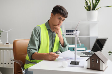 Male engineer with diagrams and wind turbine model working at table in office © Pixel-Shot