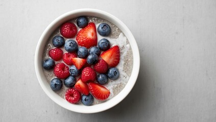 Bowl of chia pudding topped with berry salad on gray backdrop. Nutritious breakfast