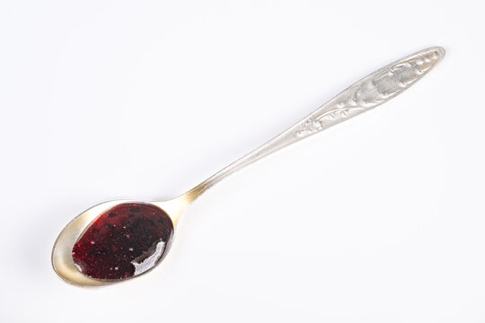 Silver spoon with currant jam on white background glossy deep red jam ornate handle minimal studio lighting highcontrast texture focus breakfast condiment concept