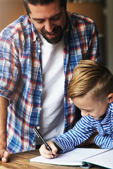 Happy, child or dad with writing homework at table for study support, language activity and help....