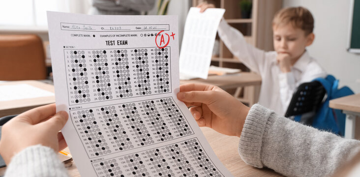 Schoolgirl with results of test at desk in classroom, closeup