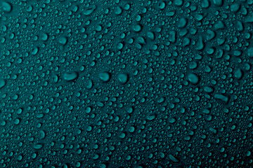 Water droplets on a dark surface create a textured pattern in a close-up view during early morning hours