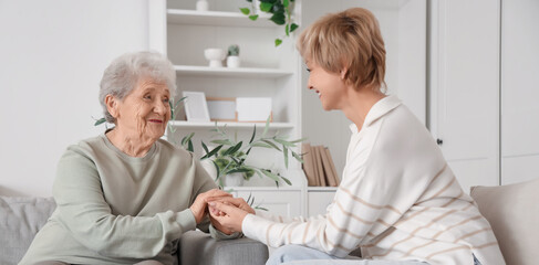 Obraz premium Mature woman with her mother holding hands on sofa at home