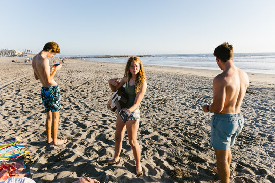 Group of teens on the beach in swimsuits with a guitar