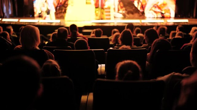 Spectators sitting in rows of chairs, observing a brightly lit stage during a show