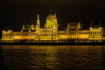 Obraz premium The Hungarian Parliament Building at night with lights and illumination, panorama view over the Danube river on a chilling winter day