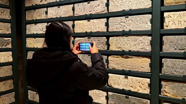 Tourist documents carved medieval stone tablets inside a historic castle exhibition hall